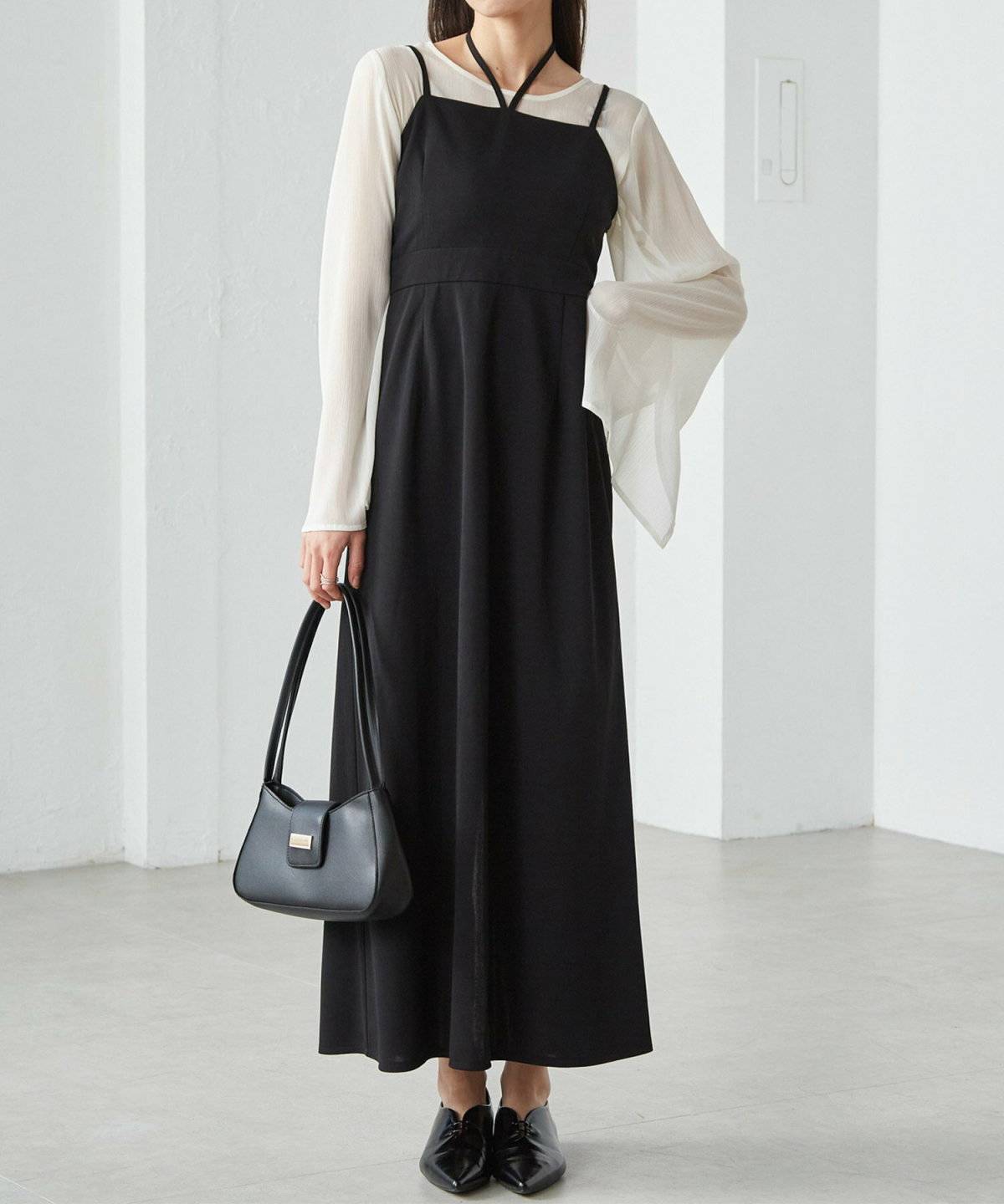 シアートップスに黒のキャミワンピースを合わせた女性