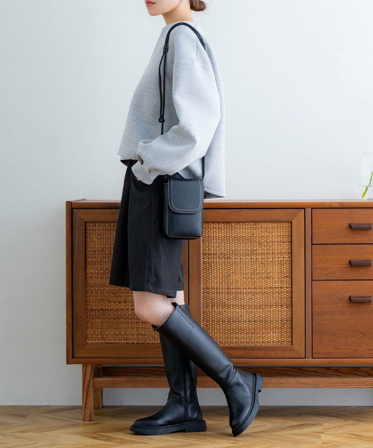 グレーのブルゾンに黒のショートパンツを合わせた女性