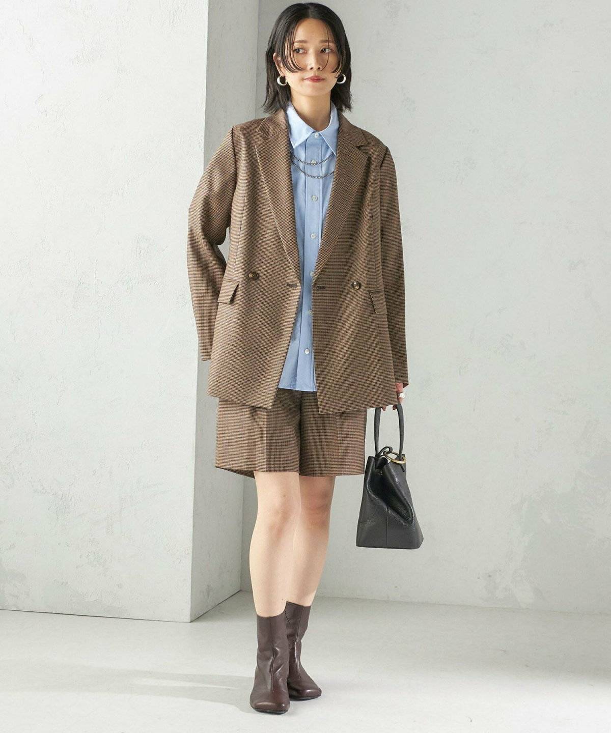 ブラウンのチェック柄ジャケットにショートパンツを合わせた女性
