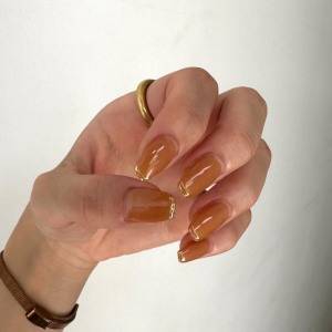 仕草まで絵になる。ゴールドラインが上品に華やぐ「オレンジネイル」