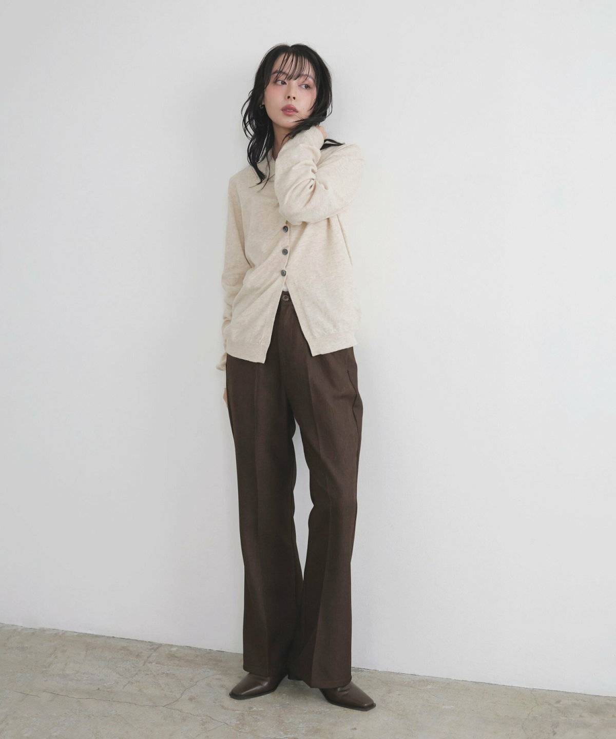 白トップスにブラウンのパンツを合わせた女性