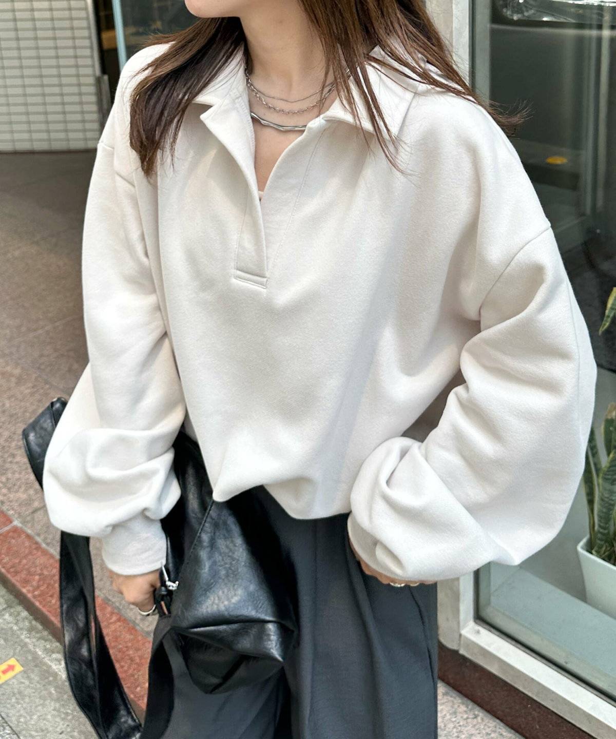 グレーのスウェットに黒のハイウエストパンツを合わせた女性