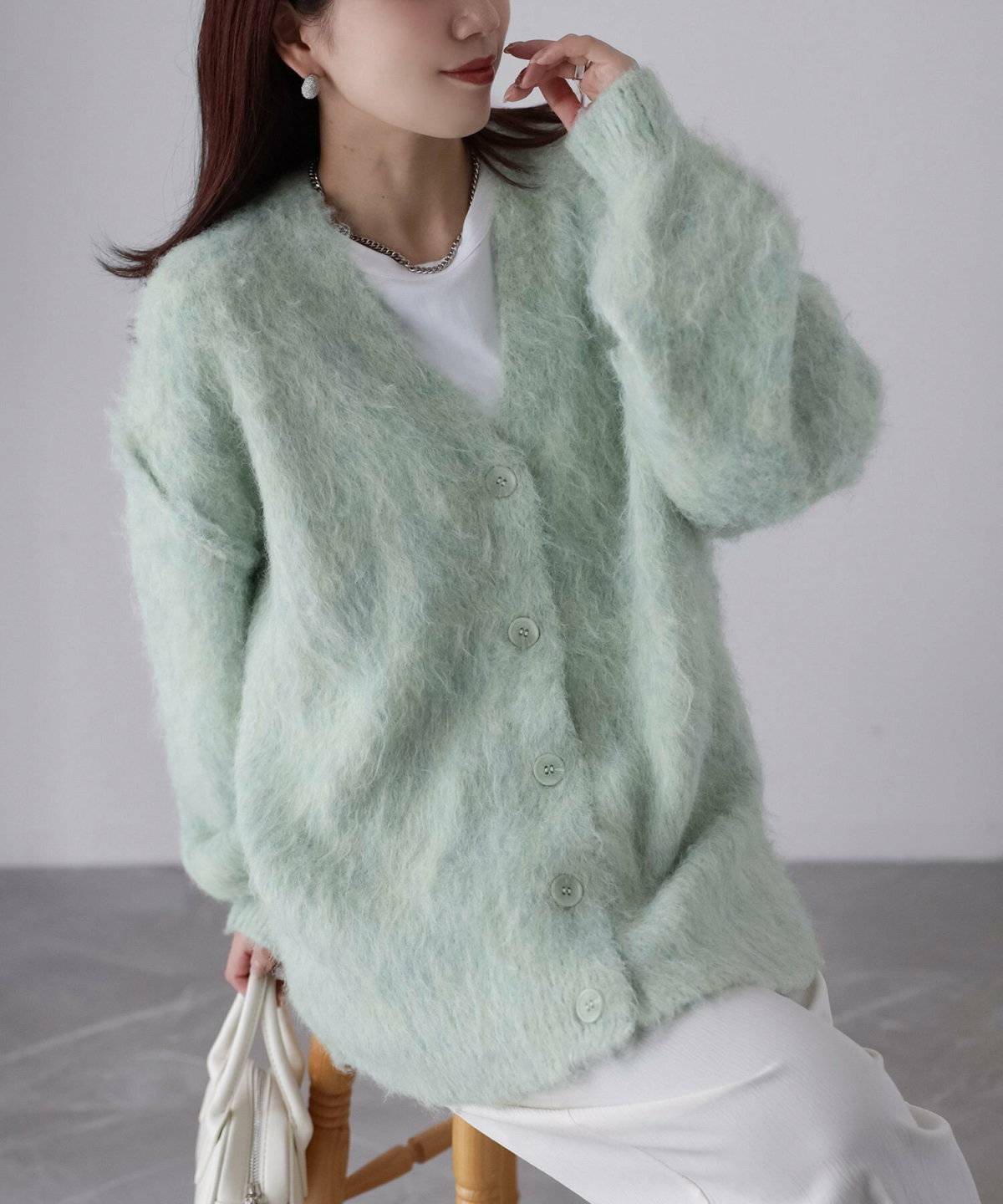 白Tシャツにパンツを合わせてグリーンのカーディガンを合わせた女性