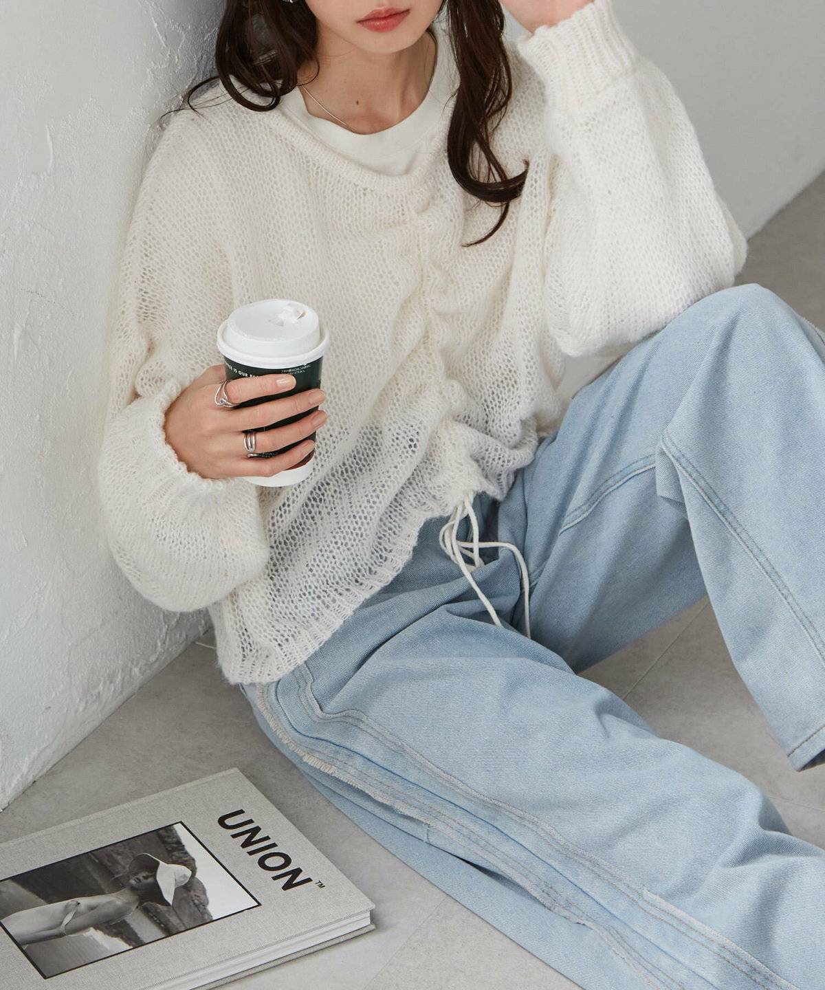 ブルーのニットにデニムを合わせた女性