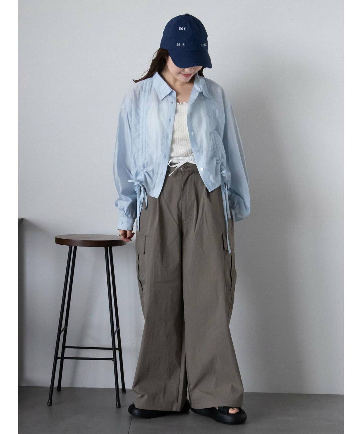 ベージュのシャツにグレーのパンツを合わせた女性