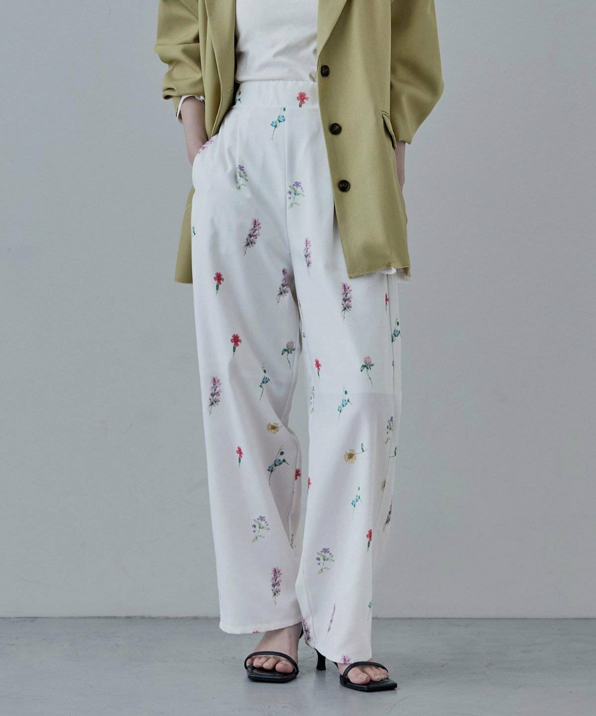 ベージュのトップスに花柄パンツを合わせてブルーのカーディガンを羽織った女性