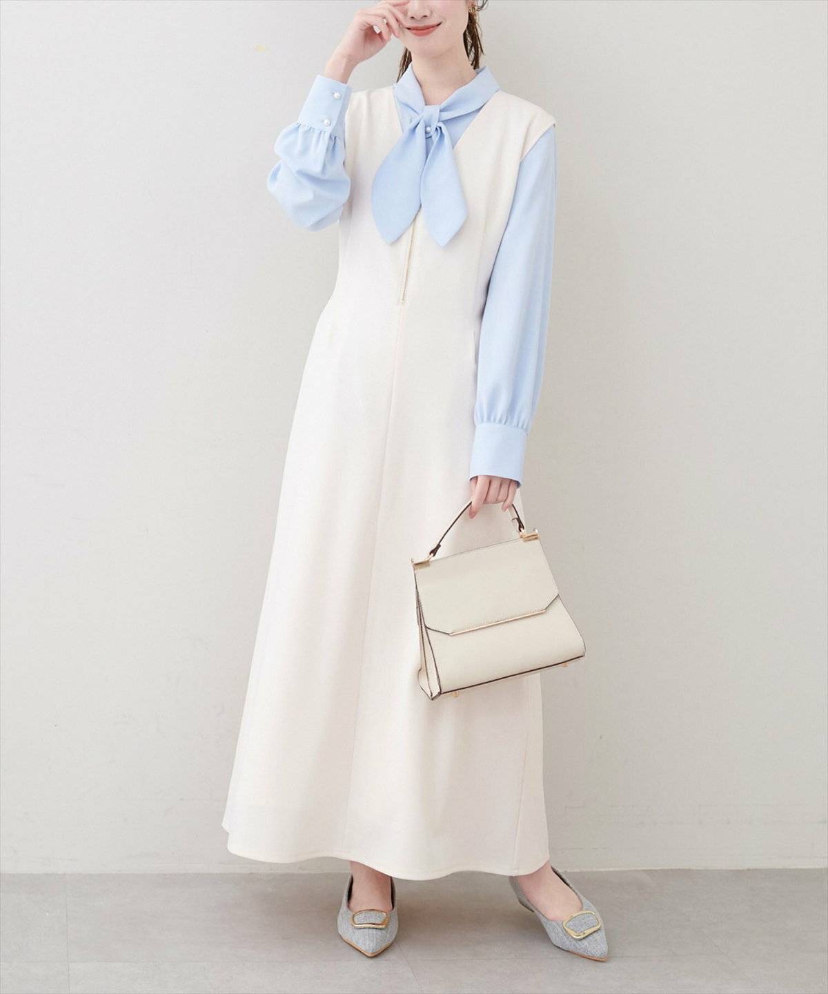 ブルーのブラウスに白のジャンパースカートを合わせた女性