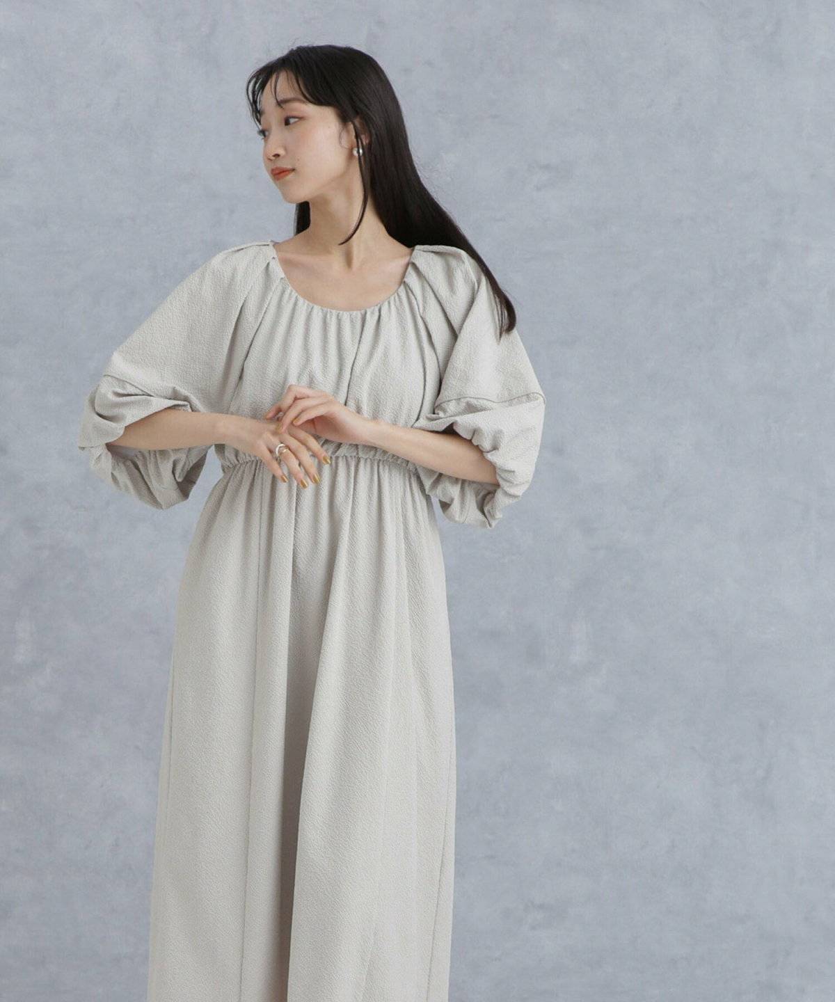 ベージュのストライプ柄ワンピースを着た女性