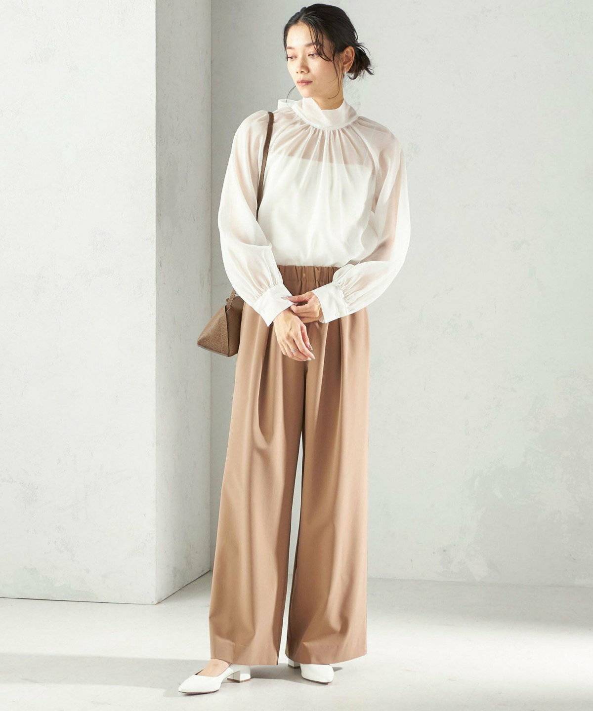 白トップスにベージュのパンツを合わせた女性