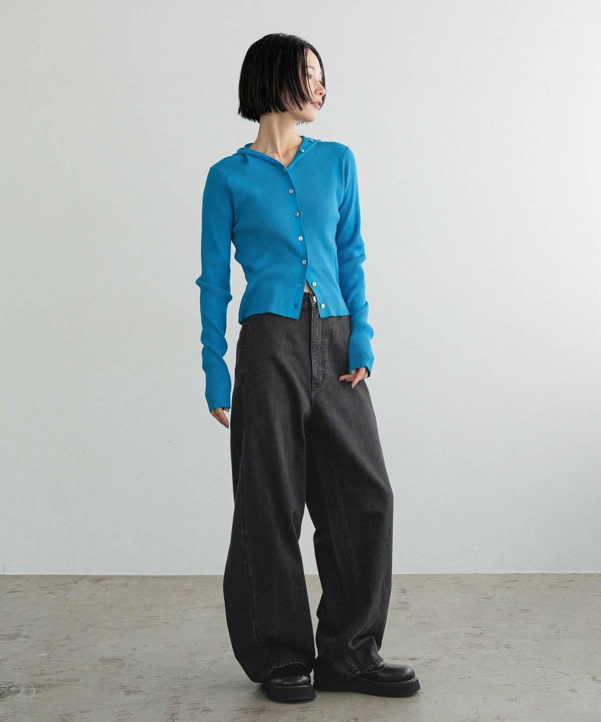 ブルーのトップスに黒デニムを合わせた女性