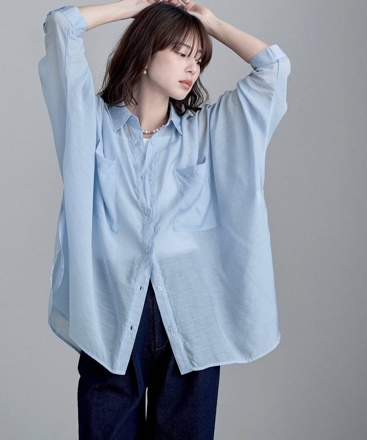 ブルーのブラウスに黒パンツを合わせた女性