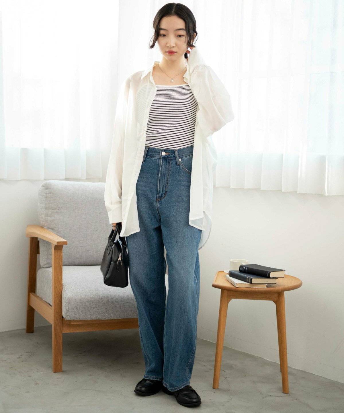 ボーダー柄のキャミソールに白カーディガンを羽織ってデニムを合わせた女性