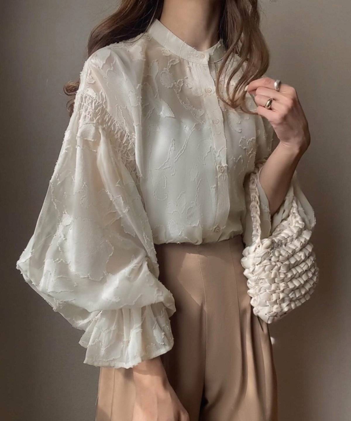 ベージュのブラウスにブラウンのパンツを合わせた女性