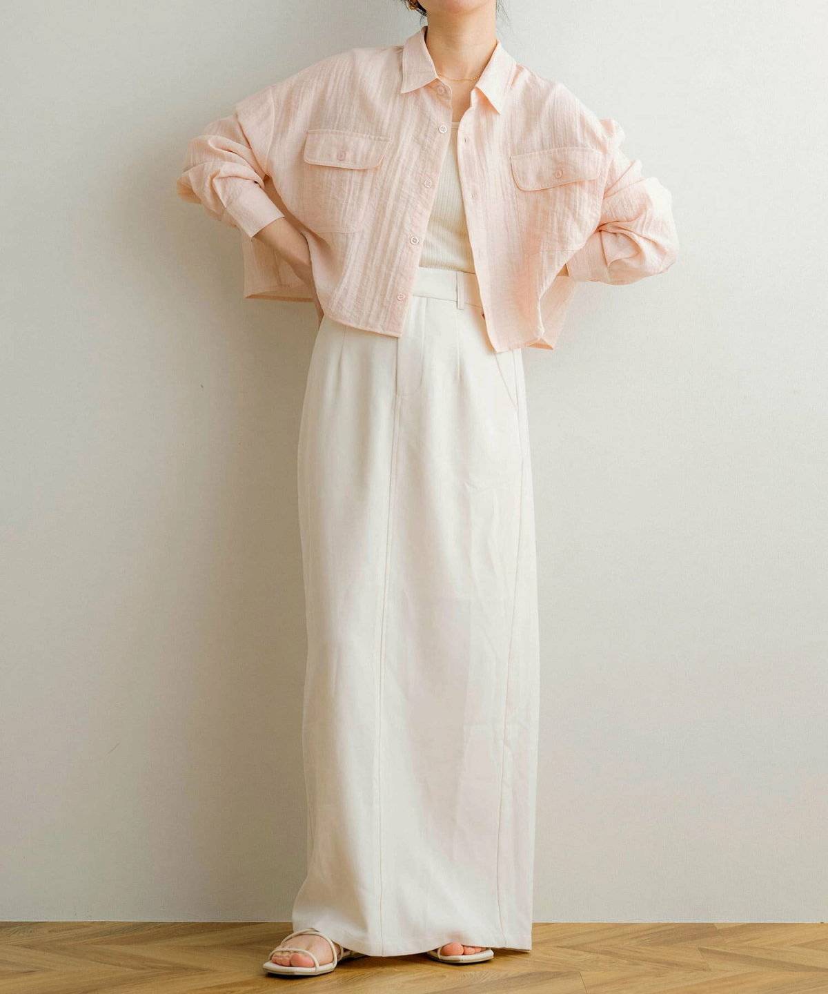 ホワイトコーデにピンクのジャケットを羽織った女性