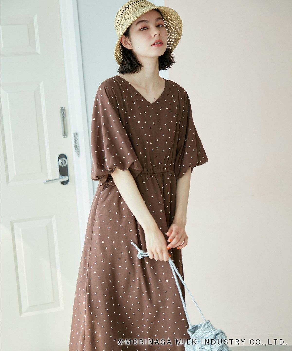 ドット柄のワンピースにかごバッグを合わせた女性