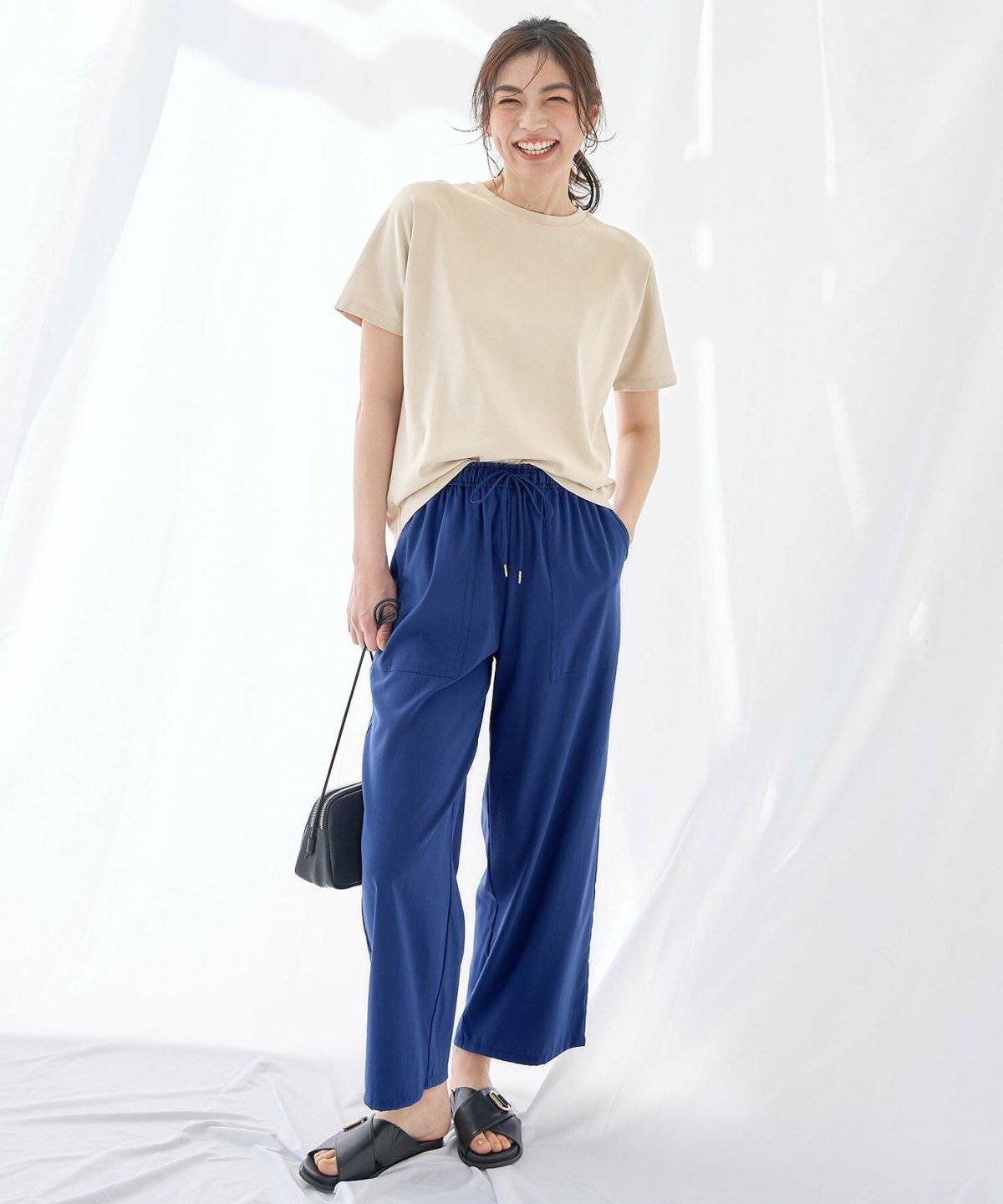 ベージュのTシャツにカラーパンツを合わせた女性