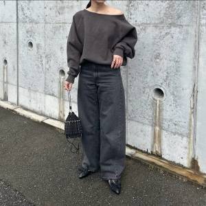  グレーのトップスにデニムパンツを合わせた女性 