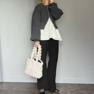  グレーのカーディガンに黒パンツを合わせた女性 
