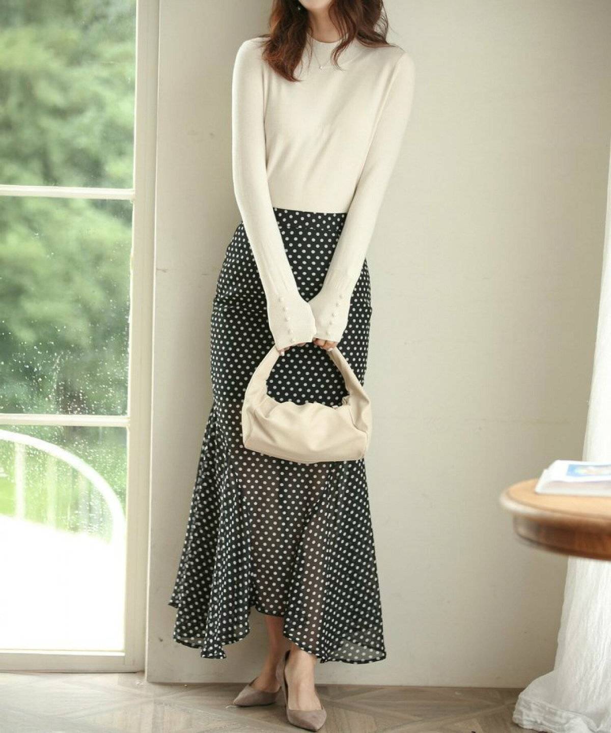 ニットに黒のドット柄スカートを合わせた女性