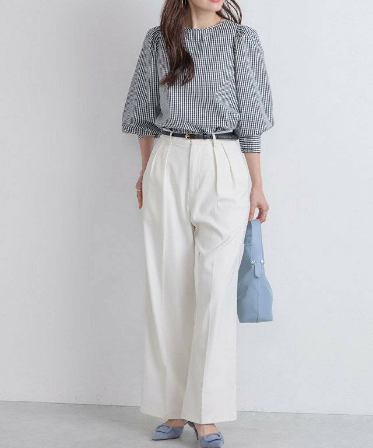 ブラウスに白のハイウエストパンツを合わせた女性