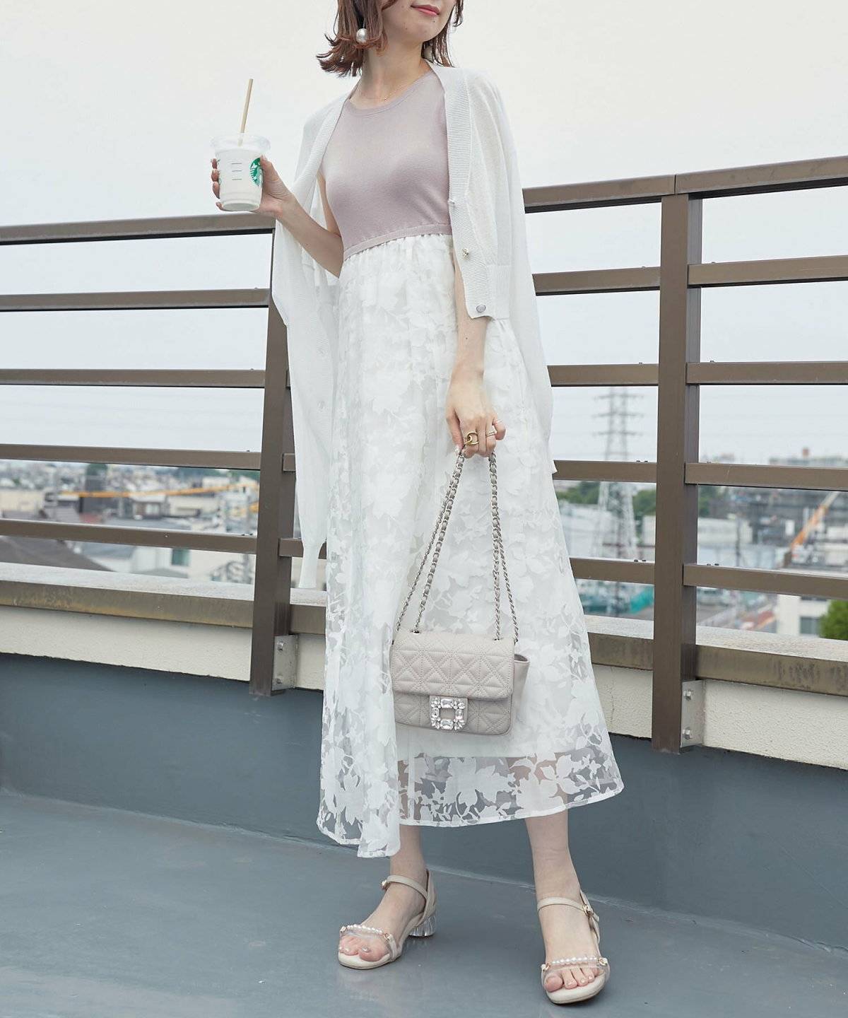 ピンクのワンピースにグレーのカーディガンを合わせた女性