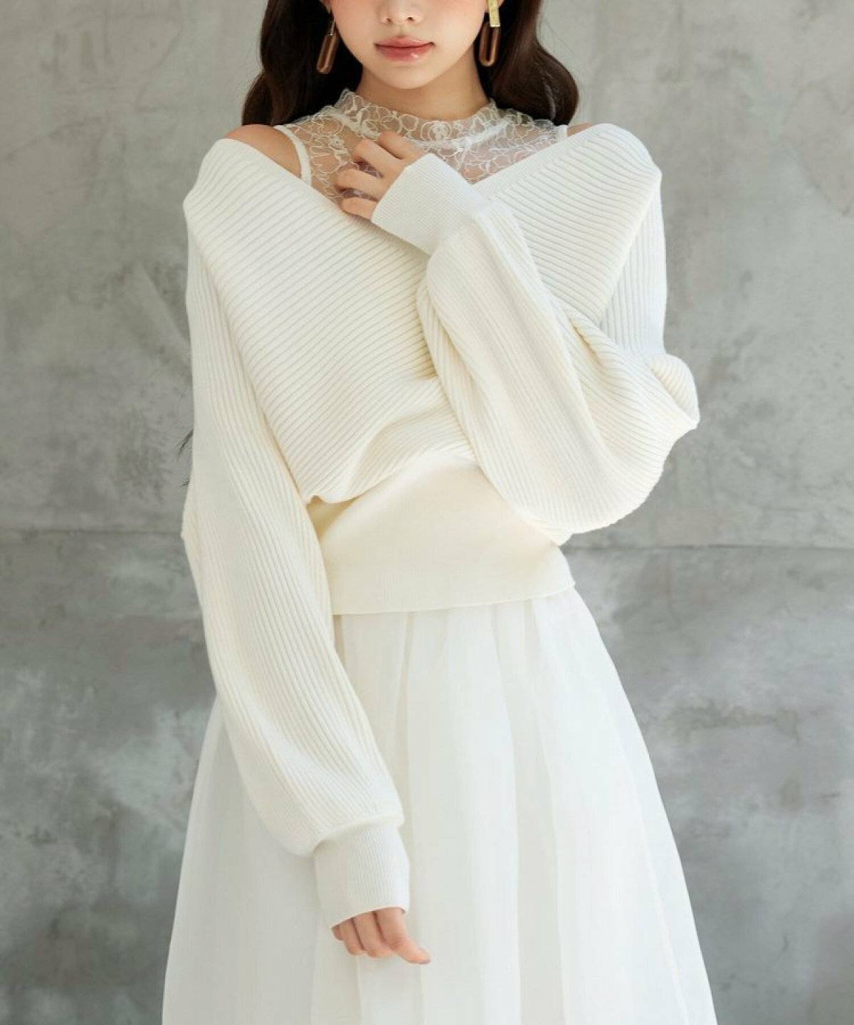 グレーのレースワンピースに白のニットを重ねた女性