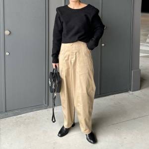  黒ニットにベージュパンツを穿いた女性 