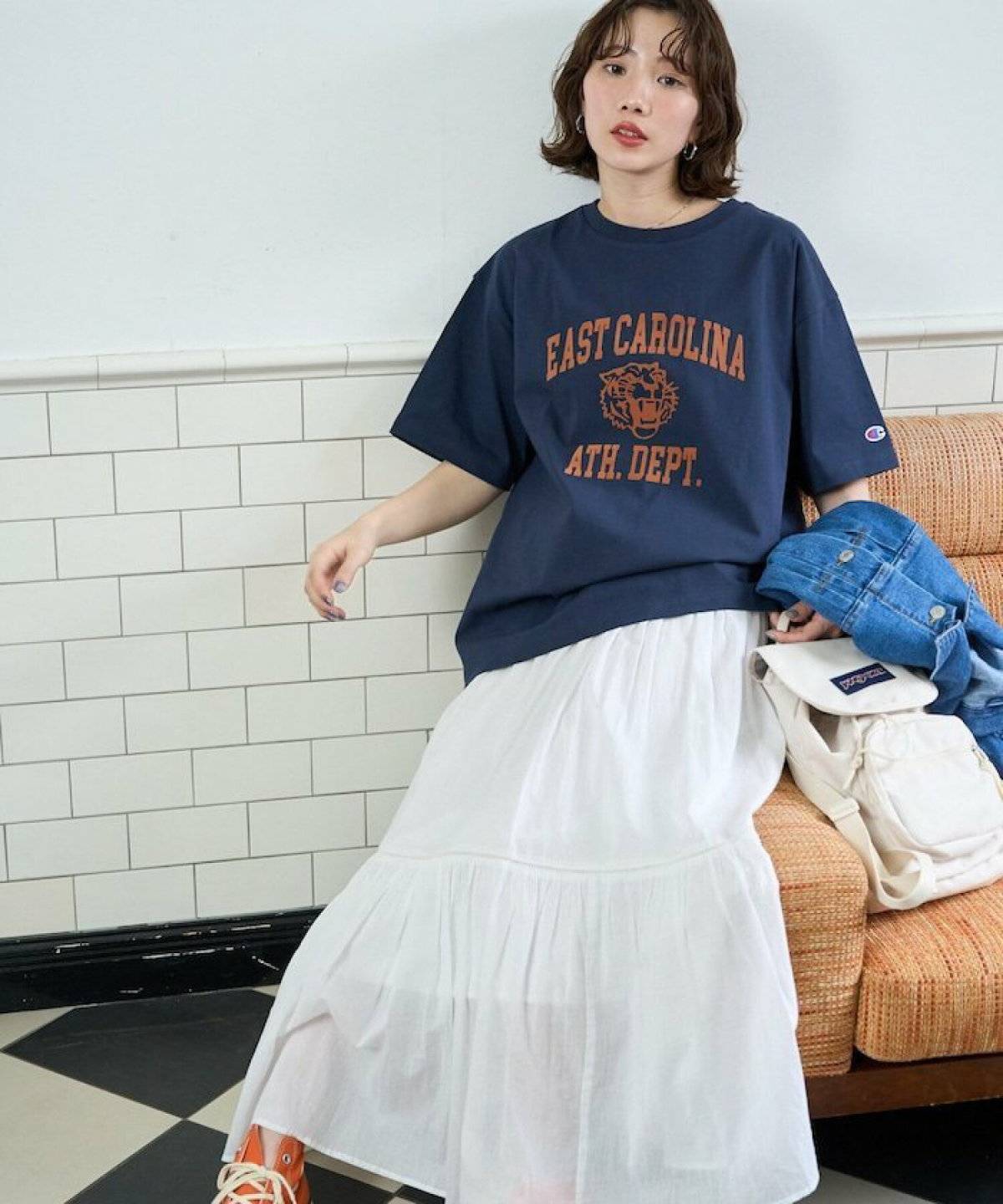 ネイビーのTシャツにホワイトスカートを合わせた女性