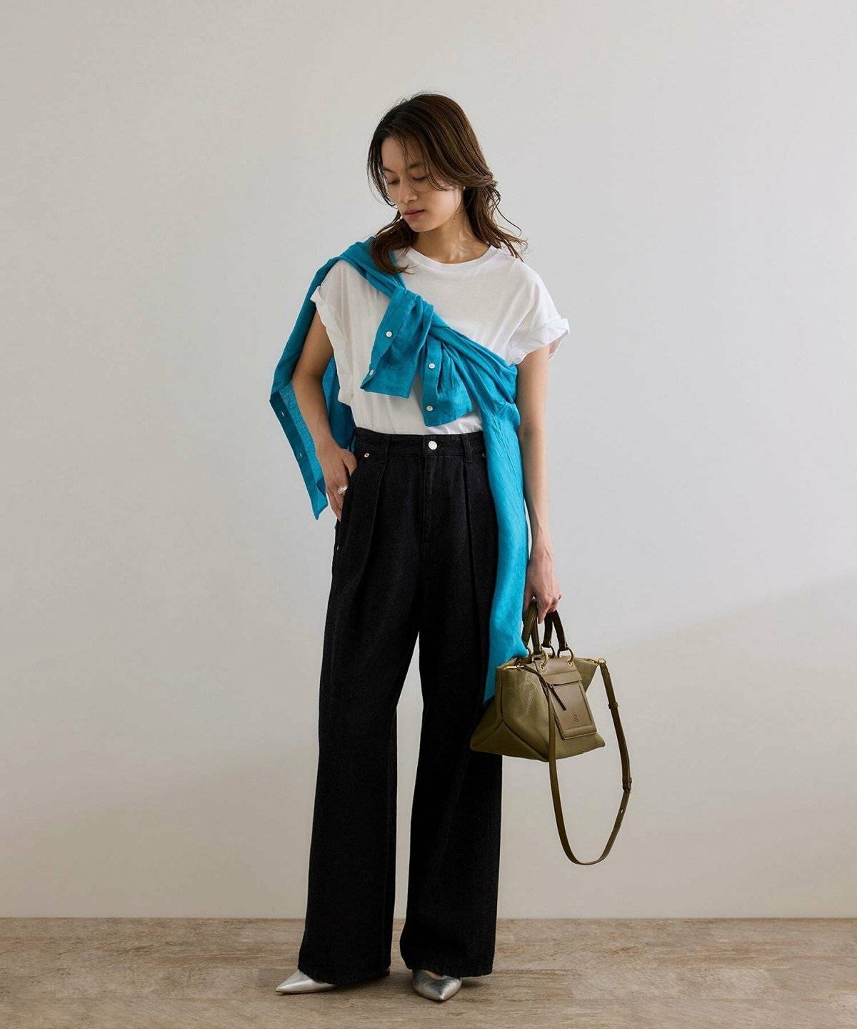 ホワイトのトップスにグレーのパンツを合わせた女性