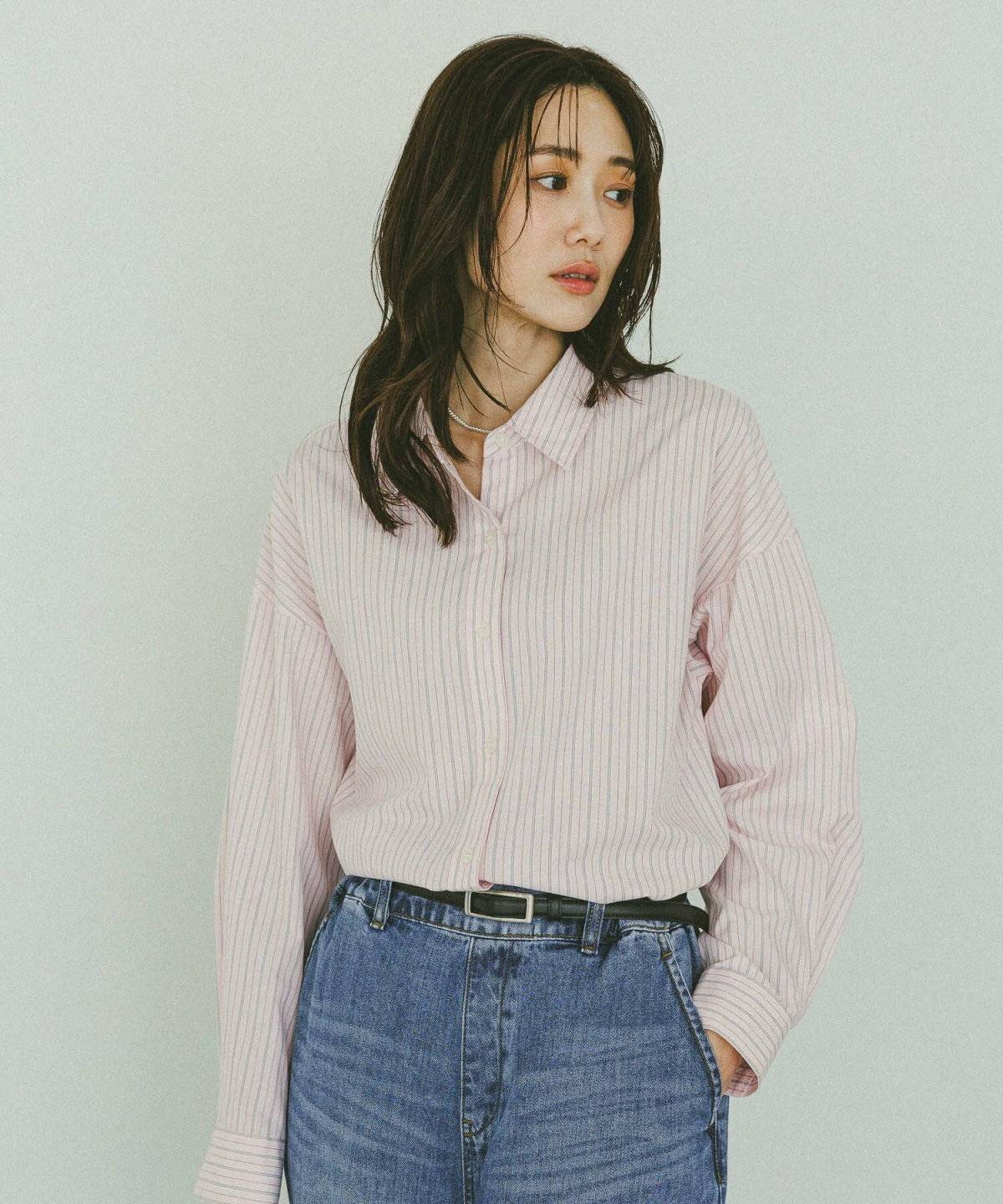 ピンクのシャツにデニムを合わせた女性