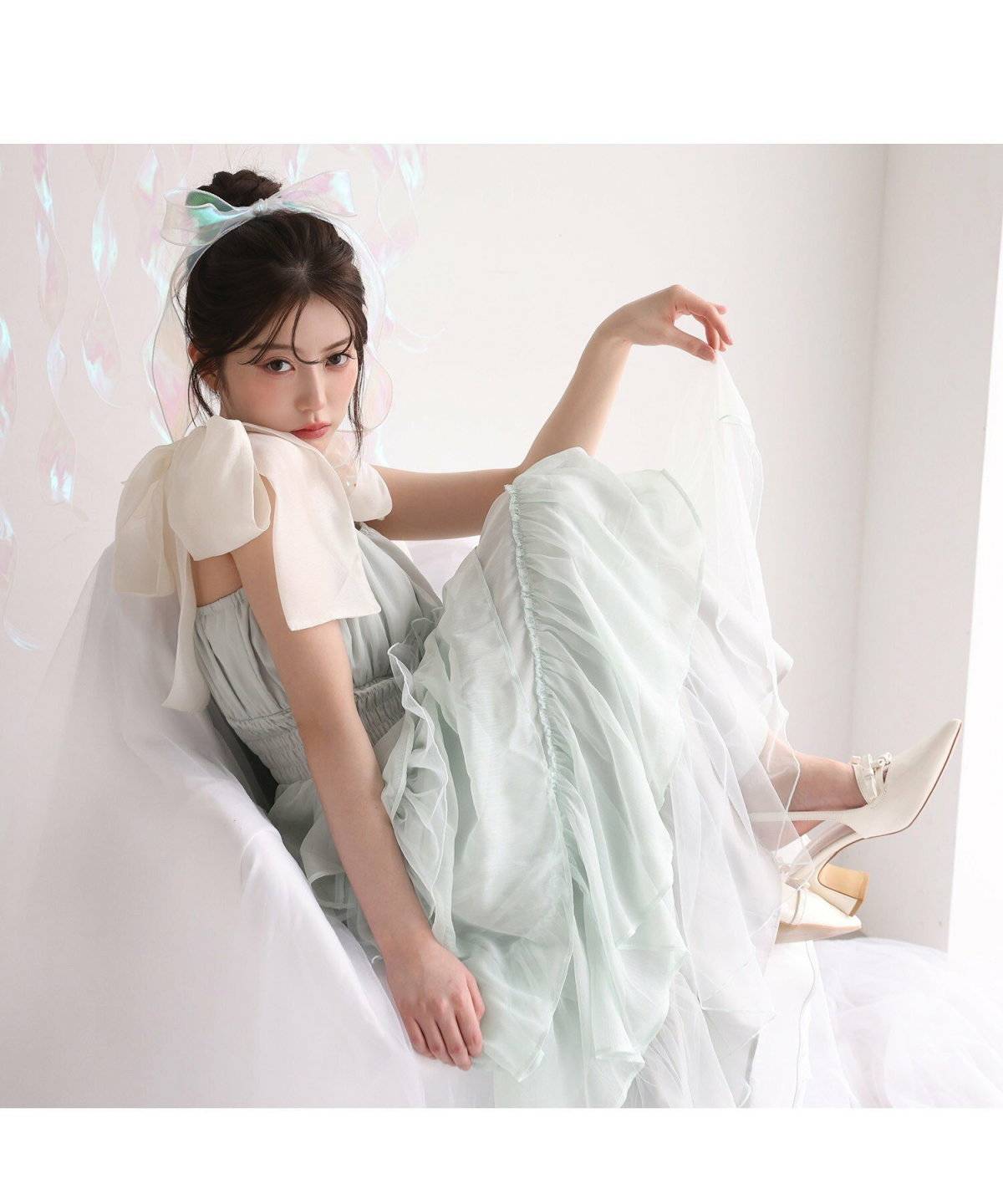 グリーンのワンピースにフリルストラップを合わせた女性