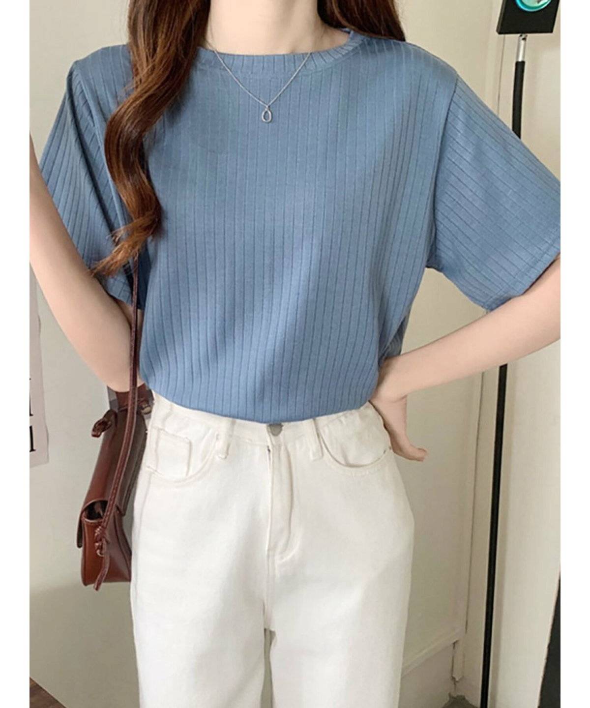 ブルーのTシャツに白デニムを合わせた女性