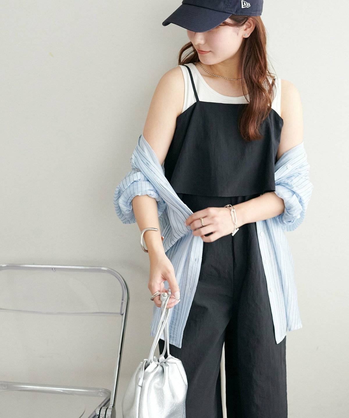 黒サロペットにブルーのシャツを羽織った女性