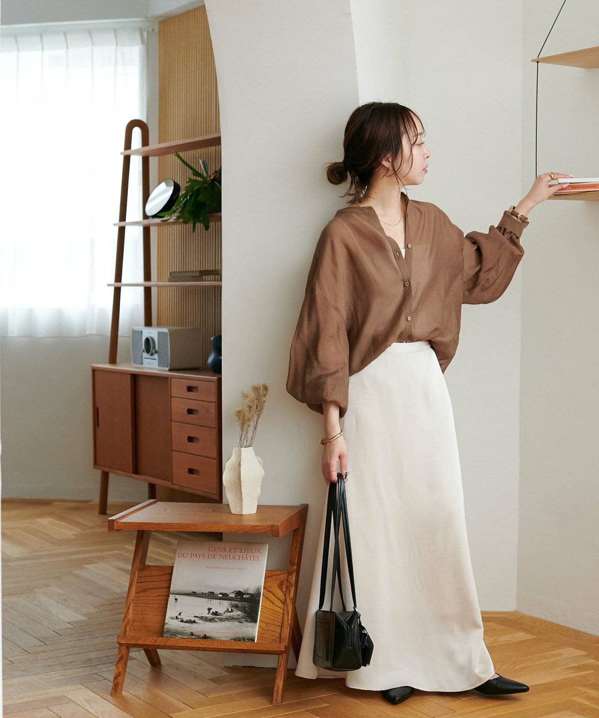 ブラウンのシアーブラウスに白スカートを合わせた女性