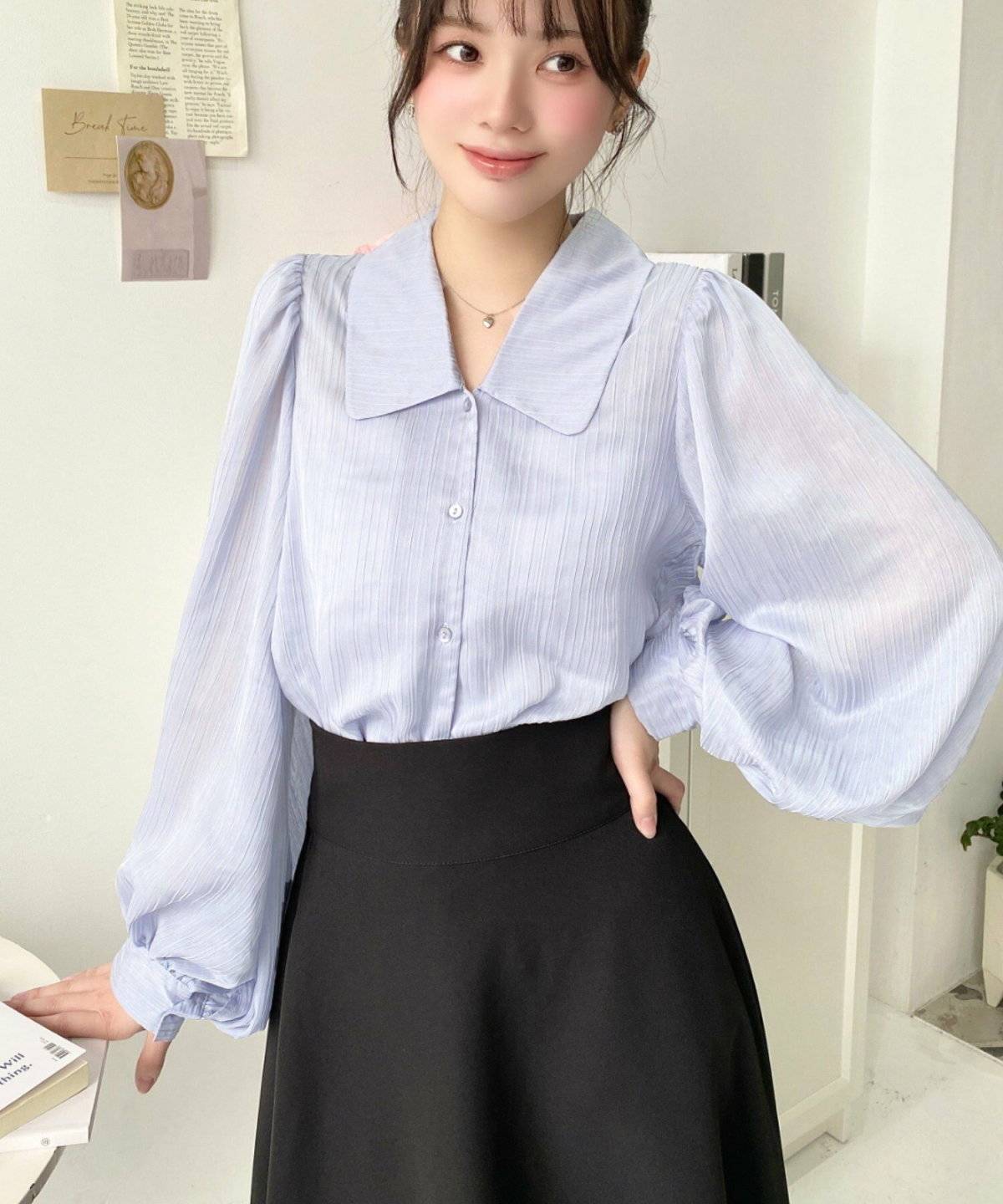 ブルーのブラウスに黒スカートを合わせた女性