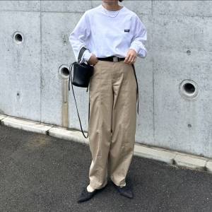  白トップスにベージュパンツを合わせた女性 