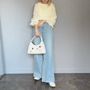  白ブラウスにデニムパンツを穿いた女性 