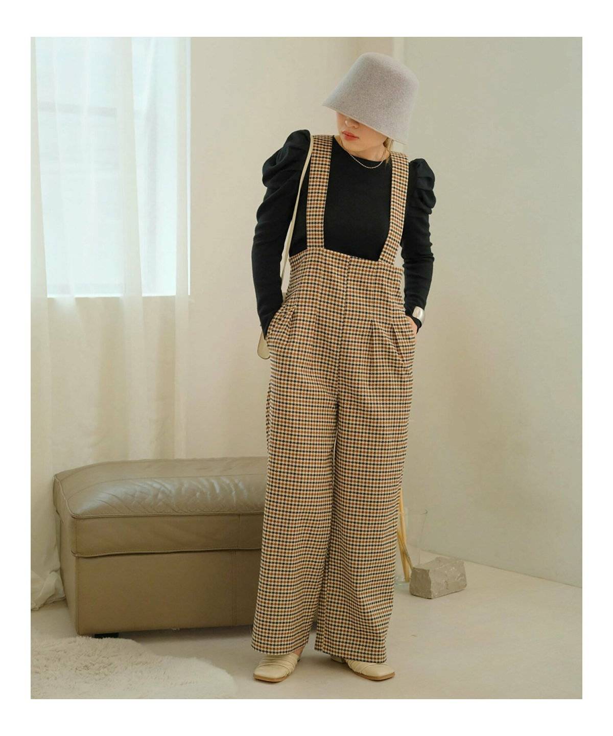 黒トップスにチェック柄パンツを合わせてファーベストを重ねた女性