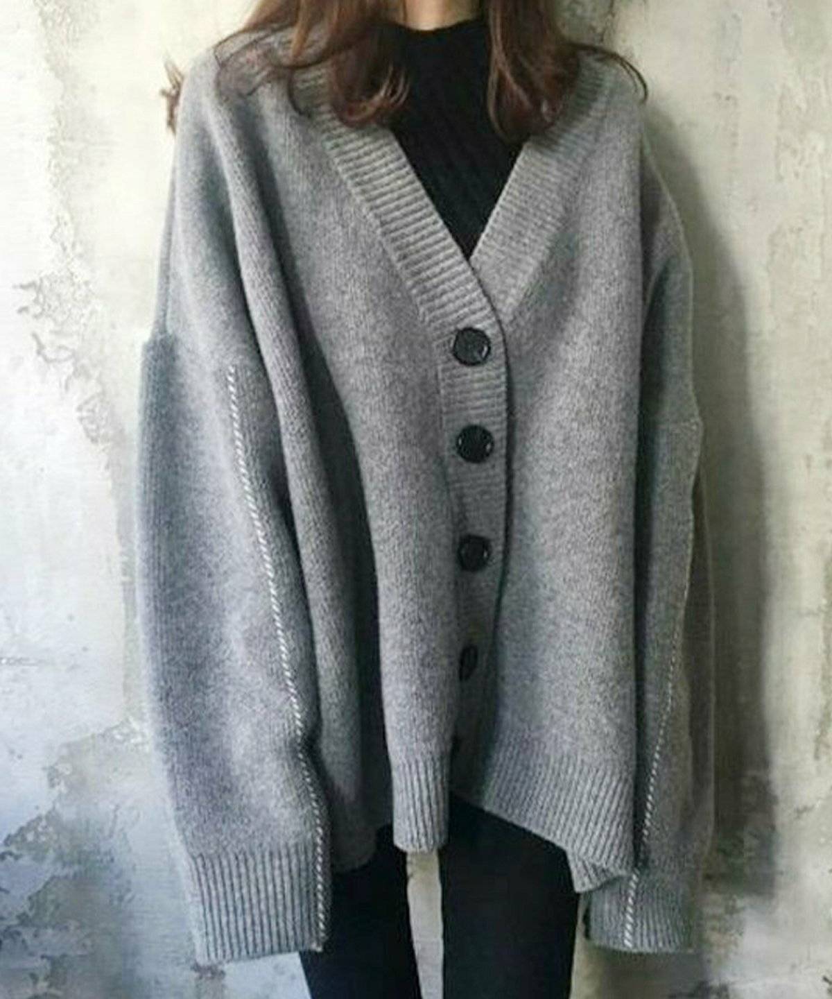 グレーのカーディガンに黒パンツを合わせた女性