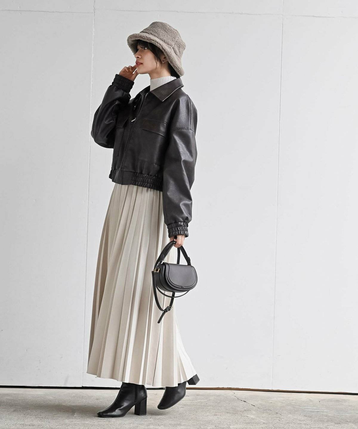 モノトーンコーデにベージュのバケハをかぶった女性