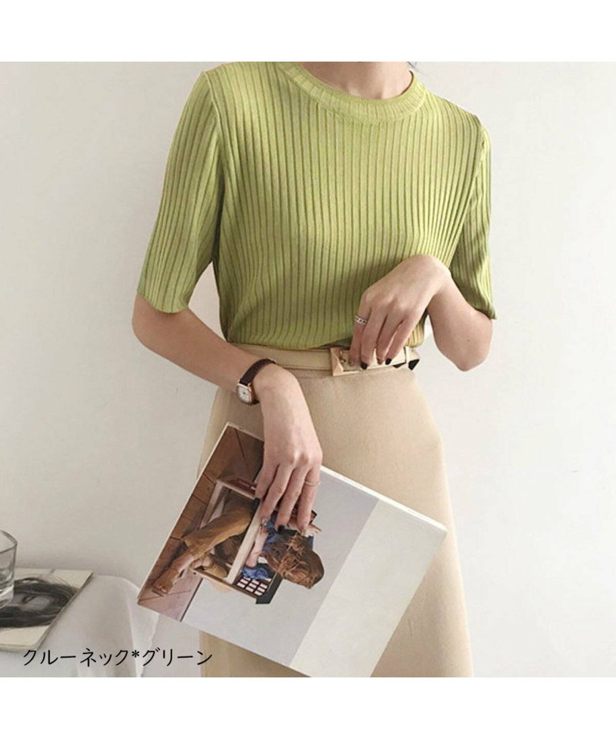 グリーンのニットにベージュのスカートを合わせた女性