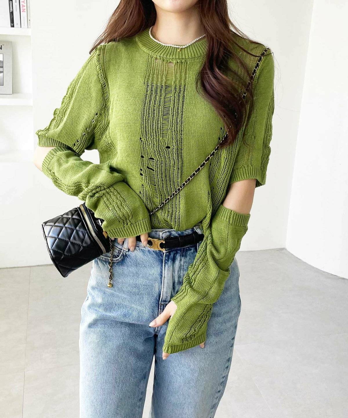 グレーのニットポンチョにデニムを合わせた女性