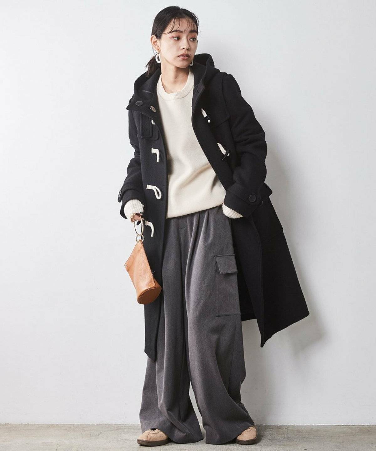 ブラウンのニットに白パンツを合わせた女性