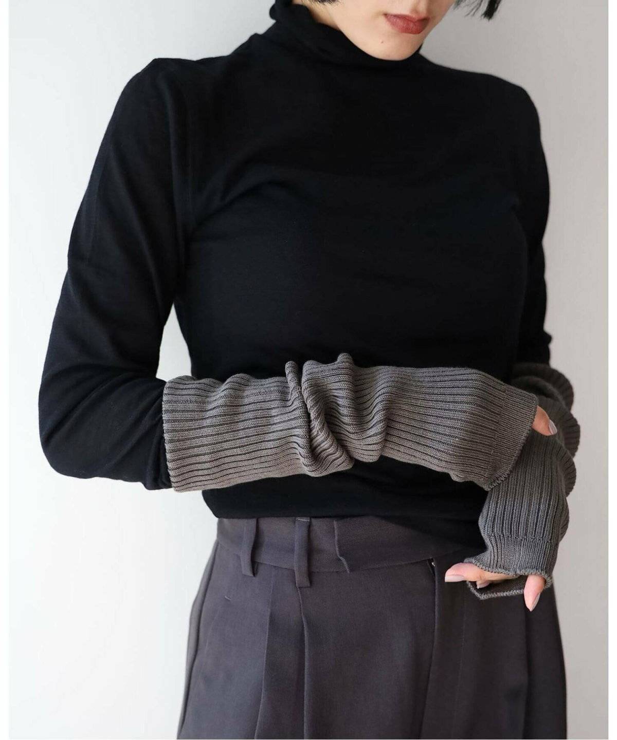 グレーのニットに黒のサロペットを合わせた女性