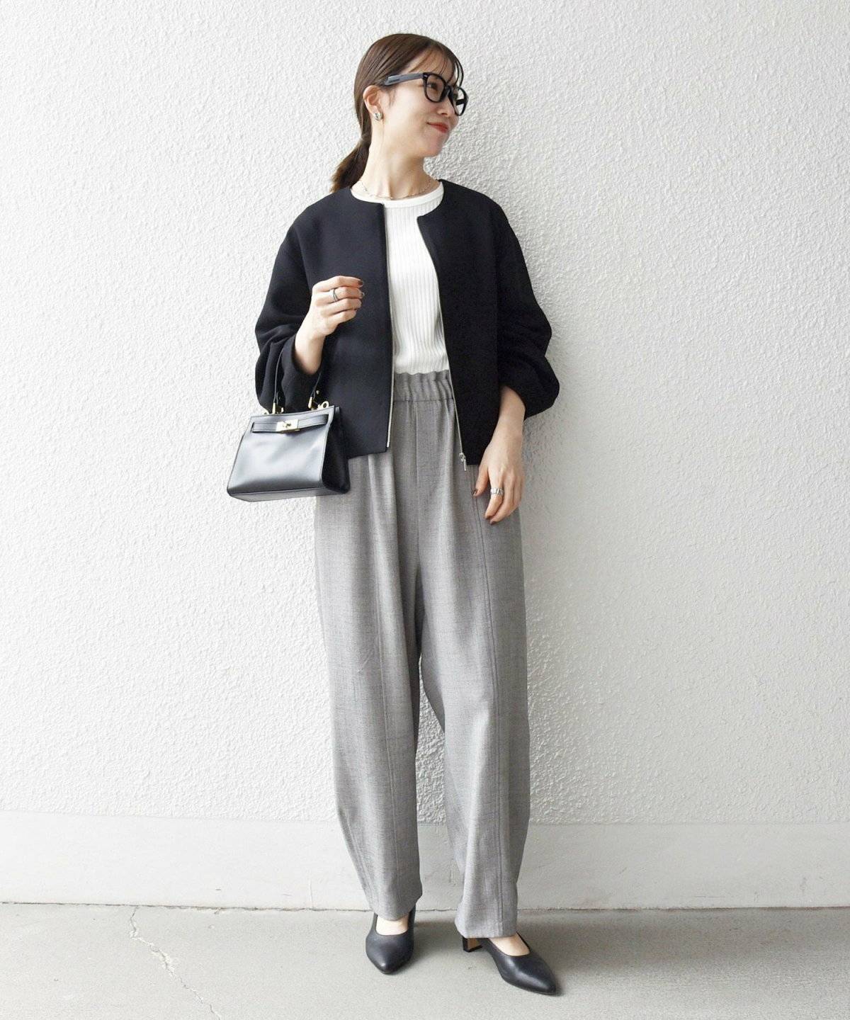 黒ブルゾンにグレーのパンツを合わせた女性