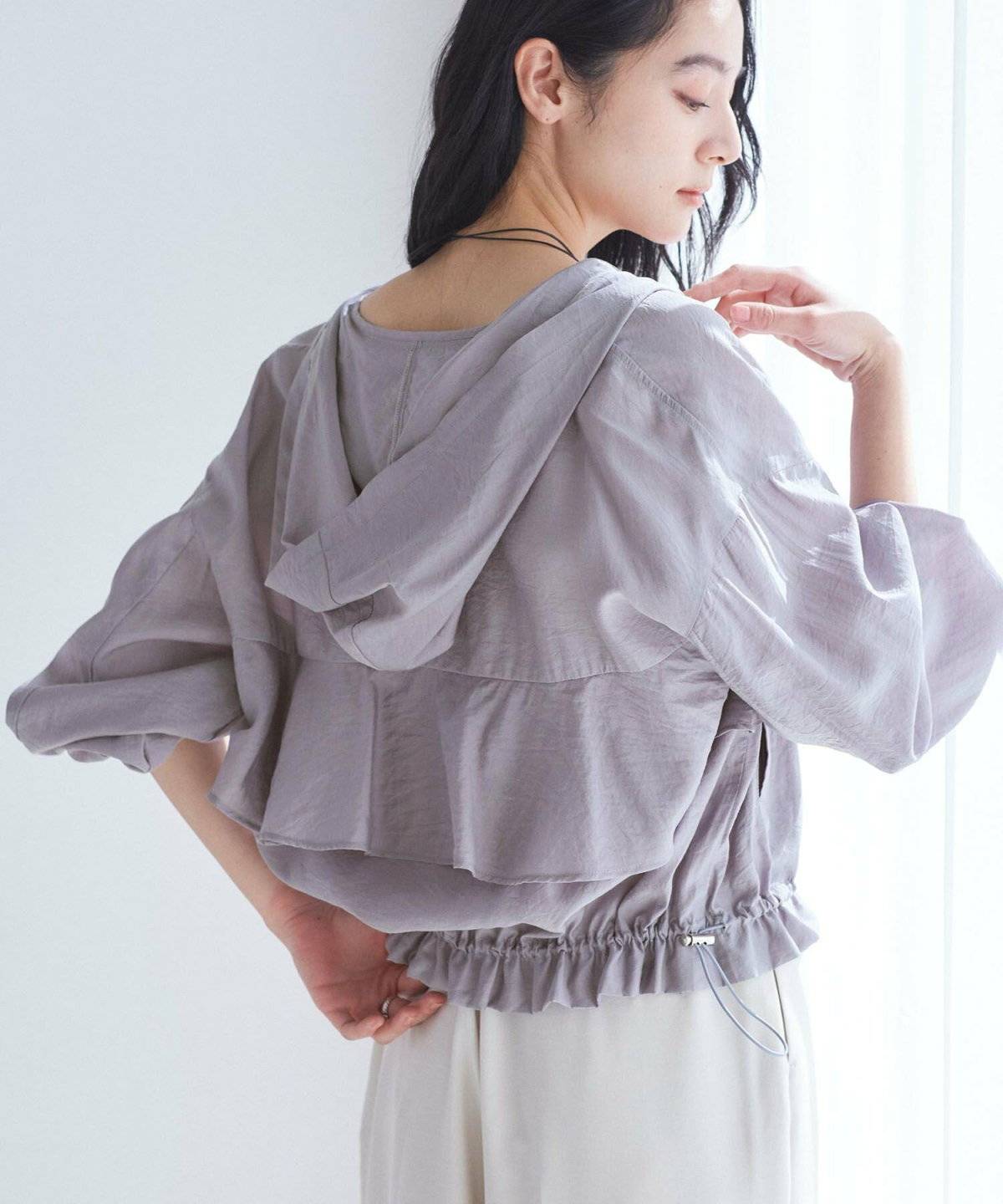 グレーのブルゾンにシルバーのスカートを合わせた女性