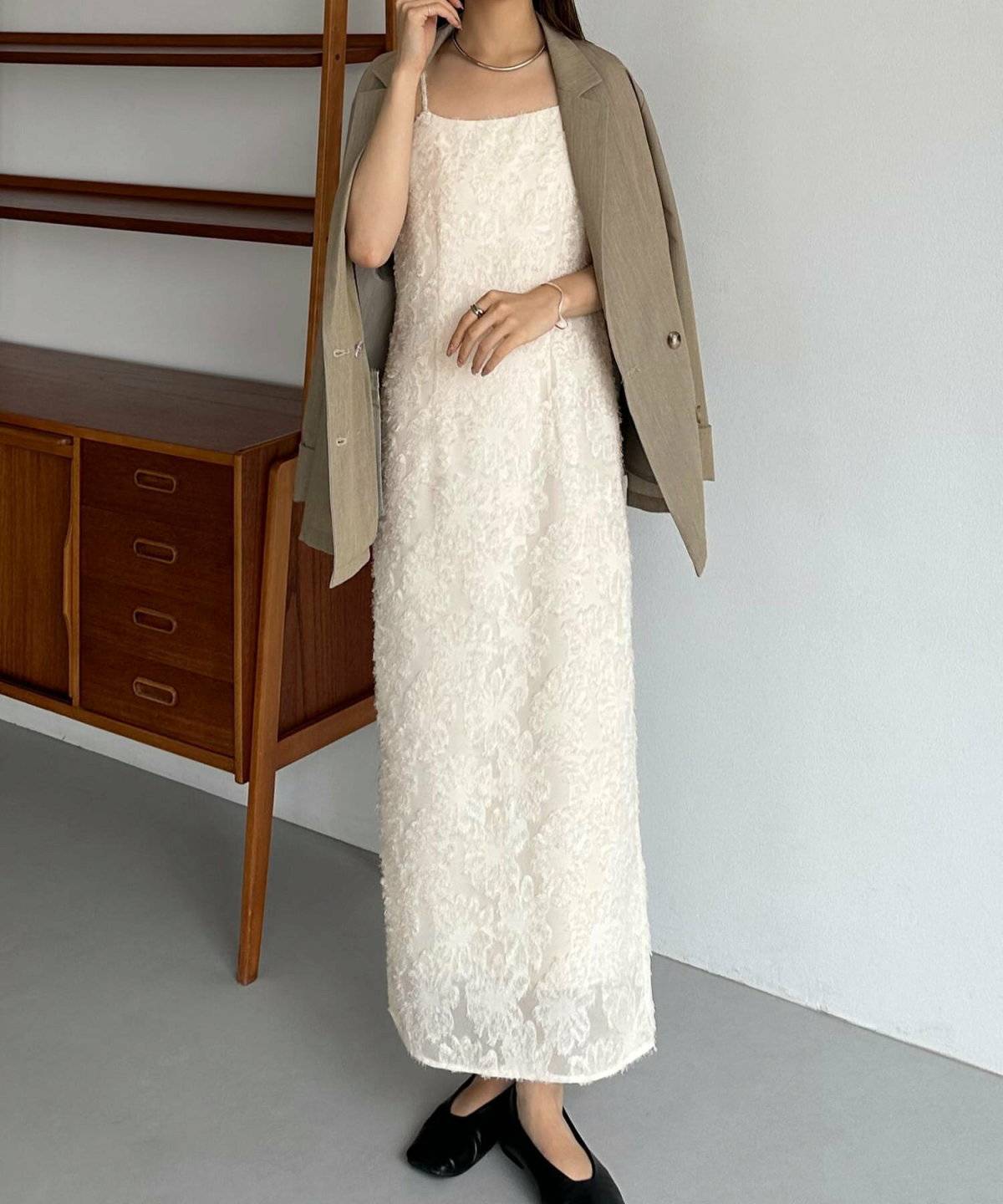 白ワンピースにベージュのアウターを羽織った女性