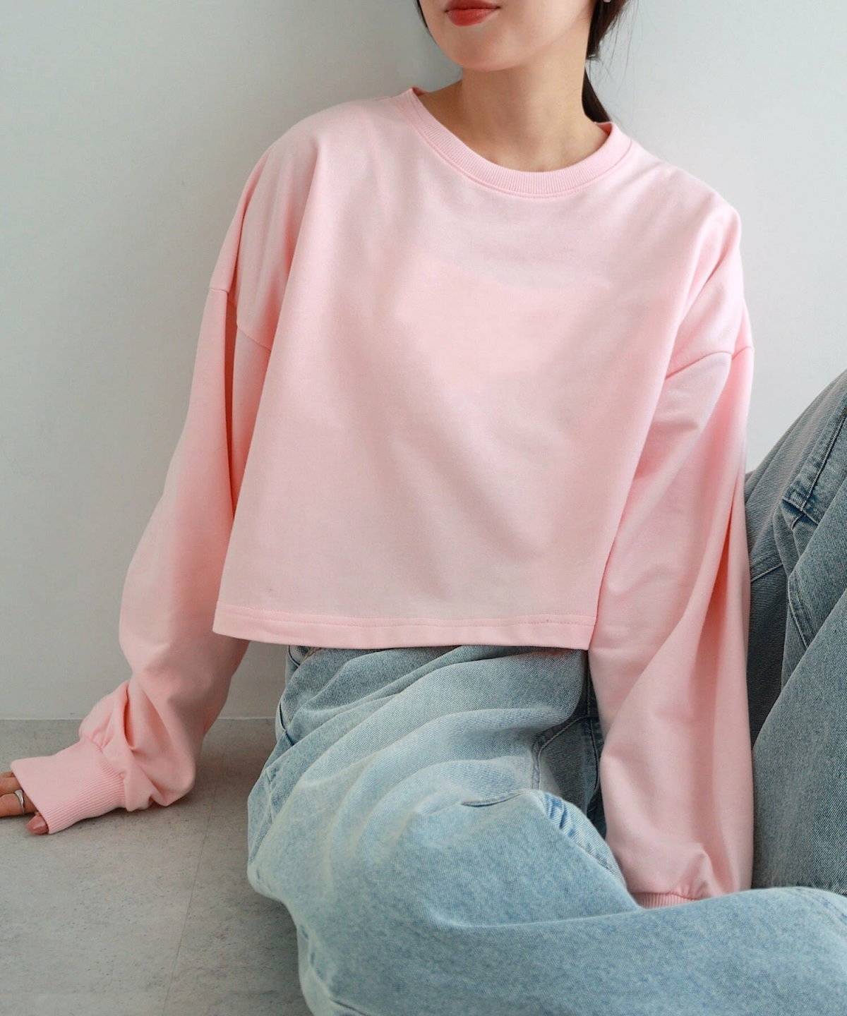 ピンクのスウェットにデニムを合わせた女性