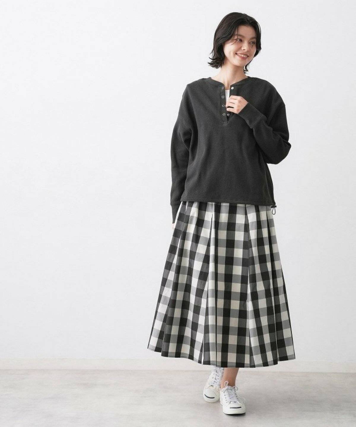 グレーのトップスにブルーの花柄スカートを合わせた女性