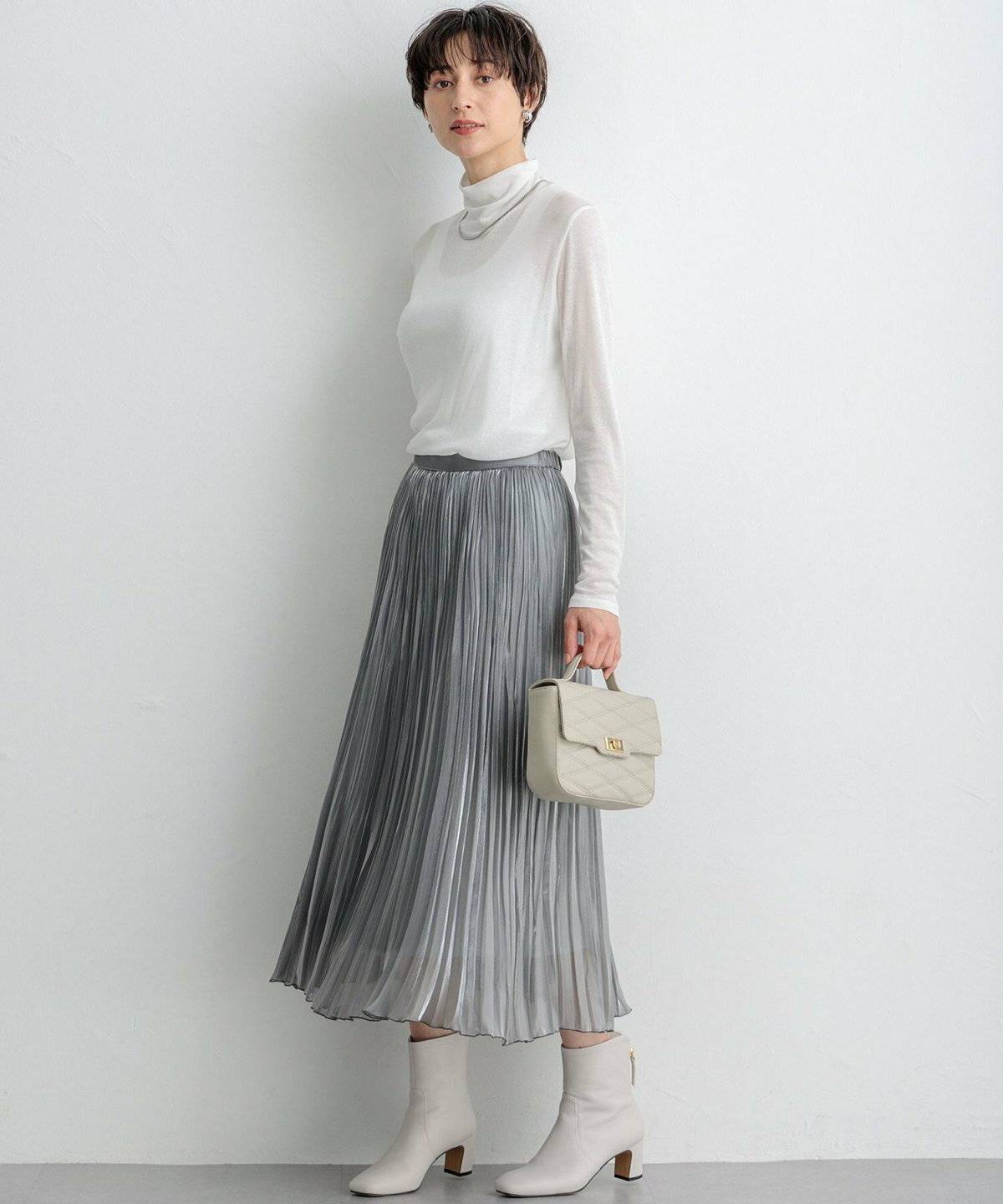 白ブラウスにシルバーのプリーツスカートを合わせた女性